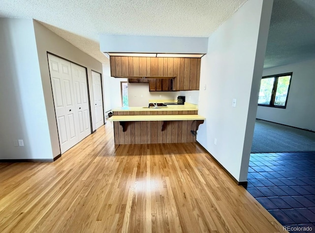 53 Douglas Dr S, Broomfield, CO 80020 - kitchen featuring a peninsula, light countertops, a breakfast bar area, a textured ceiling, and baseboards