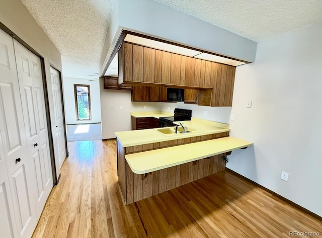 53 Douglas Dr S, Broomfield, CO 80020 - kitchen featuring black appliances, a textured ceiling, light countertops, a sink, and light wood finished floors