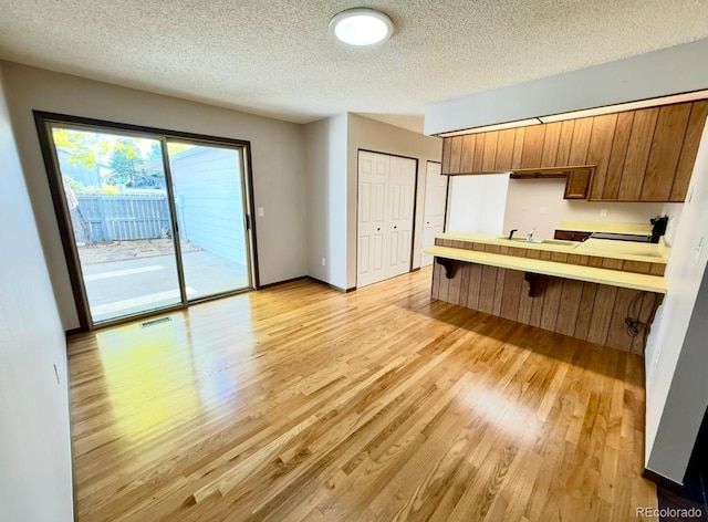 53 Douglas Dr S, Broomfield, CO 80020 - kitchen with a peninsula, light wood finished floors, a textured ceiling, brown cabinetry, and a sink