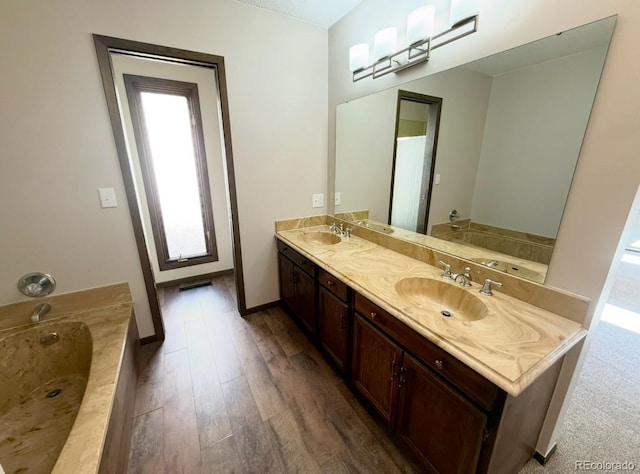 53 Douglas Dr S, Broomfield, CO 80020 - bathroom featuring double vanity, a bath, wood finished floors, and plenty of natural light