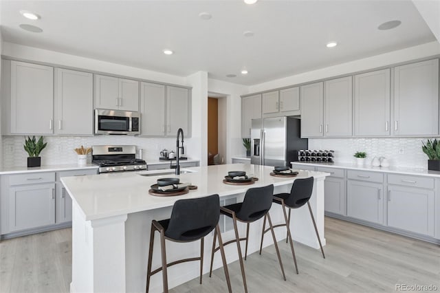 13326 Blue Amber Ct, Parker, CO 80134 - kitchen with stainless steel appliances, gray cabinetry, decorative backsplash, a kitchen island with sink, and recessed lighting