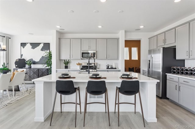 13326 Blue Amber Ct, Parker, CO 80134 - kitchen featuring stainless steel appliances, gray cabinetry, light countertops, decorative backsplash, and light wood-style floors