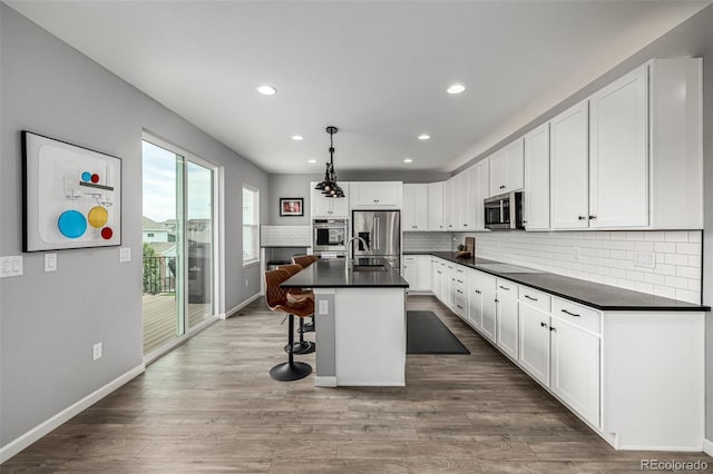 9406 Bross St, Arvada, CO 80007 - kitchen with stainless steel appliances, dark countertops, white cabinetry, decorative backsplash, and recessed lighting
