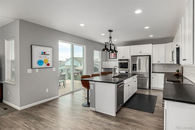 9406 Bross St, Arvada, CO 80007 - kitchen featuring stainless steel appliances, dark countertops, decorative backsplash, recessed lighting, and white cabinetry