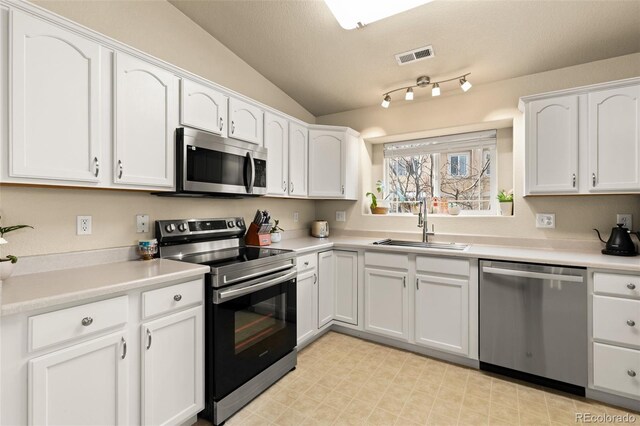1431 Madison Ridge Hts Unit D, Colorado Springs, CO 80904 - kitchen featuring appliances with stainless steel finishes, a sink, white cabinets, vaulted ceiling, and light countertops