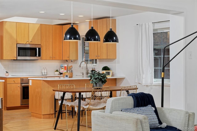 2500 Locust St, Denver, CO 80207 - kitchen with appliances with stainless steel finishes, light countertops, light wood-style flooring, backsplash, and a breakfast bar area