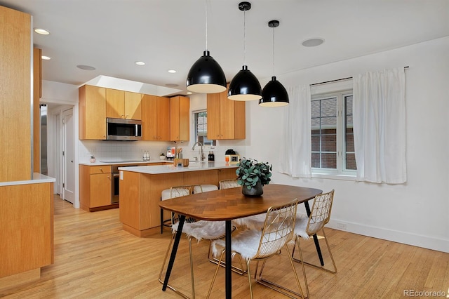 2500 Locust St, Denver, CO 80207 - kitchen with stainless steel microwave, light wood finished floors, a sink, baseboards, and a peninsula