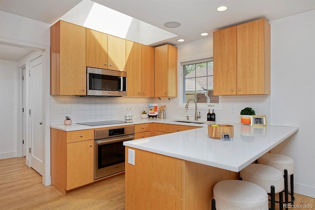 2500 Locust St, Denver, CO 80207 - kitchen with stainless steel appliances, a sink, a kitchen bar, light wood-style floors, and recessed lighting