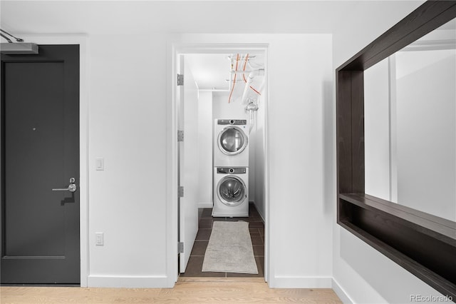 1750 Wewatta St Unit 1301, Denver, CO 80202 - laundry area featuring stacked washing machine and dryer, baseboards, and wood finished floors