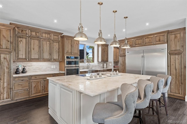 22454 Anasazi Way, Golden, CO 80401 - kitchen with appliances with stainless steel finishes, brown cabinets, a center island, decorative backsplash, and recessed lighting