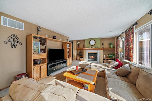 carpeted living area featuring a tiled fireplace, a textured ceiling, and visible vents