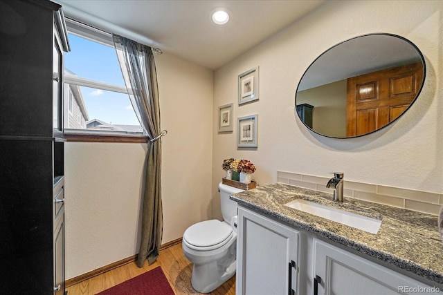 bathroom with vanity, toilet, recessed lighting, baseboards, and wood finished floors