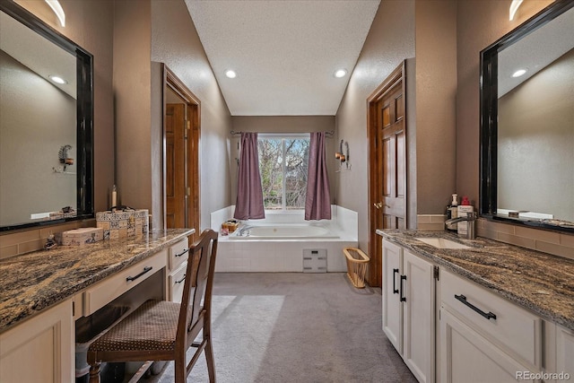 full bathroom featuring a textured ceiling, a bath, vanity, a textured wall, and recessed lighting