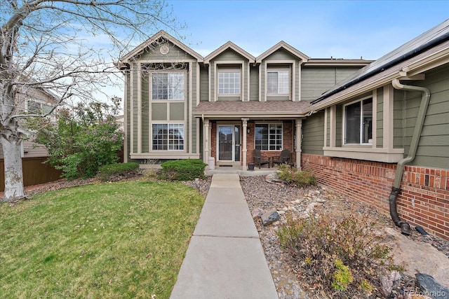 view of front of house featuring covered porch, brick siding, solar panels, and a front lawn