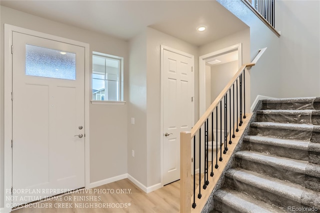 foyer entrance featuring stairs, wood finished floors, and baseboards