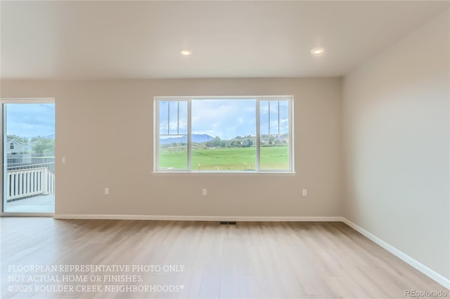 empty room featuring light wood-style flooring, visible vents, baseboards, and recessed lighting