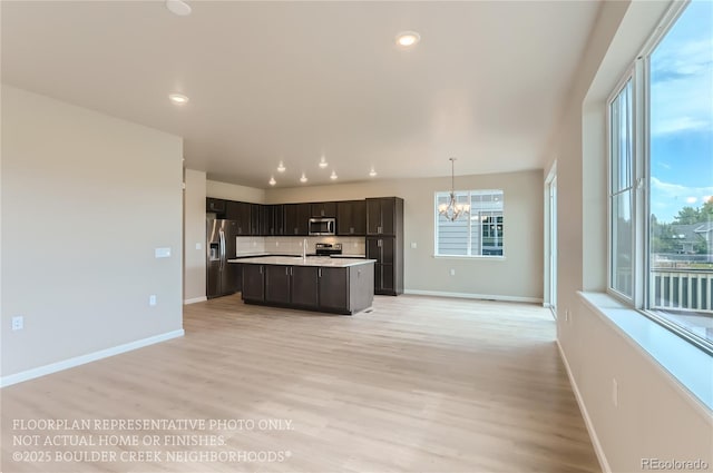 kitchen with a notable chandelier, open floor plan, light countertops, appliances with stainless steel finishes, and light wood finished floors