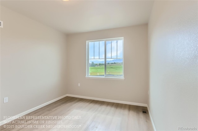 unfurnished room featuring visible vents, baseboards, and wood finished floors