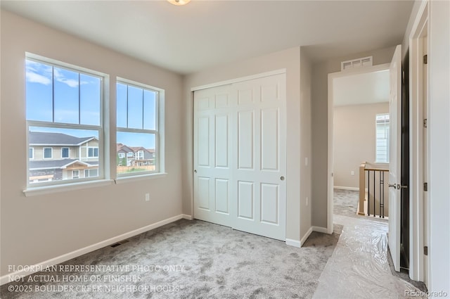 unfurnished bedroom with a closet, multiple windows, visible vents, and baseboards