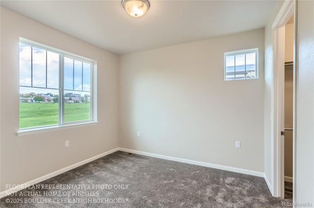 empty room with dark colored carpet and baseboards