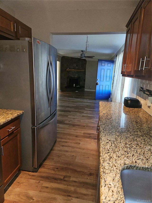 kitchen with light stone counters, stainless steel refrigerator, dark hardwood / wood-style flooring, and tasteful backsplash