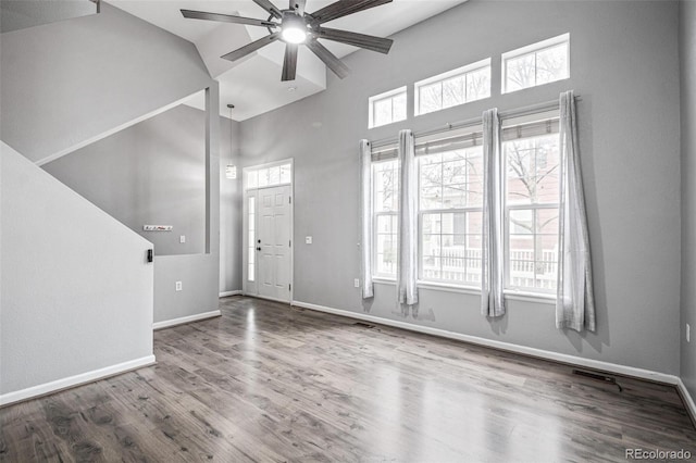 unfurnished living room featuring high vaulted ceiling, a ceiling fan, wood finished floors, baseboards, and plenty of natural light
