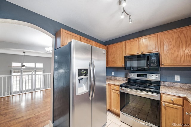 kitchen with stainless steel appliances, light countertops, ceiling fan, arched walkways, and light tile patterned floors