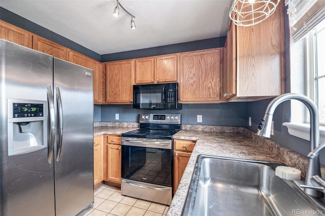 kitchen with stainless steel appliances, a sink, light tile patterned floors, light countertops, and track lighting