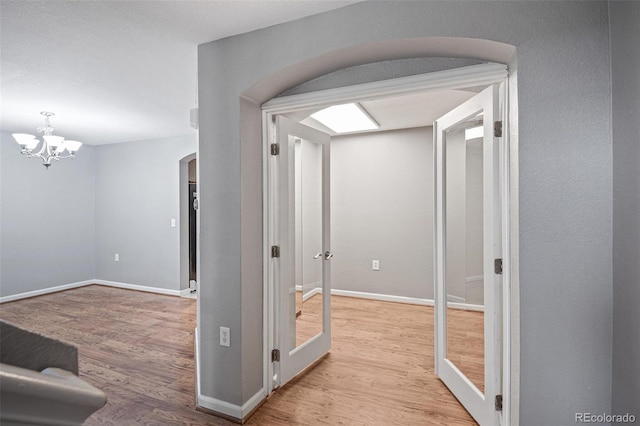 hallway with arched walkways, wood finished floors, and baseboards