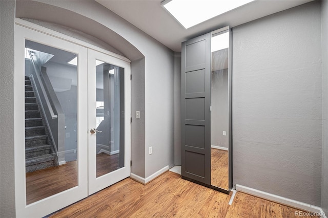 doorway to outside featuring french doors, light wood-style floors, stairway, and baseboards