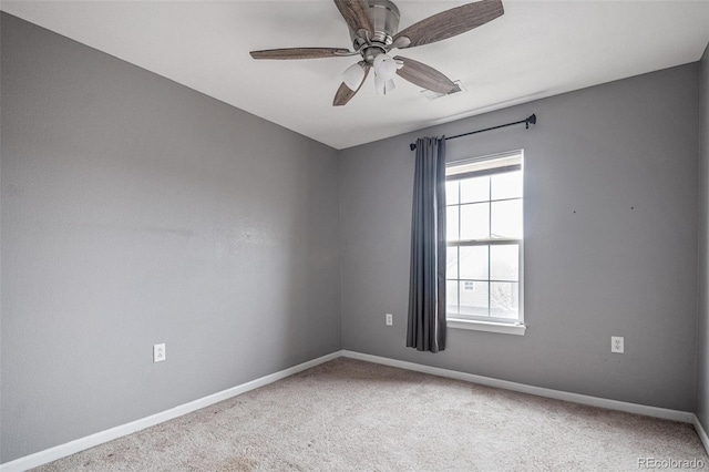 carpeted spare room featuring baseboards and a ceiling fan