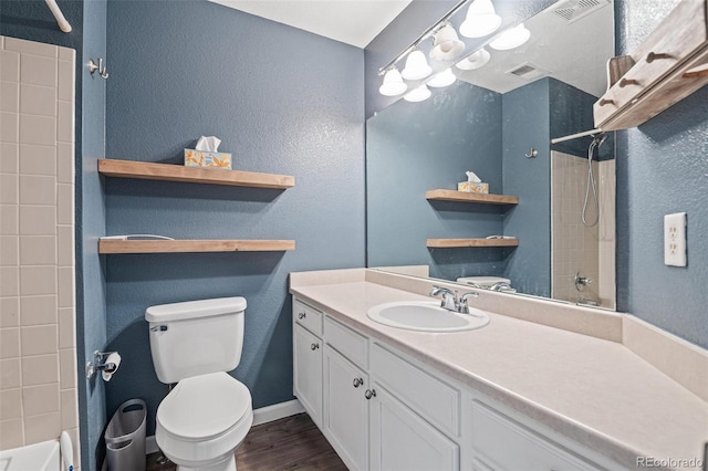 bathroom with a textured wall, toilet, wood finished floors, shower / washtub combination, and vanity