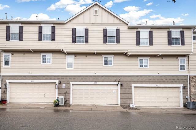back of property with central air condition unit, a garage, and board and batten siding