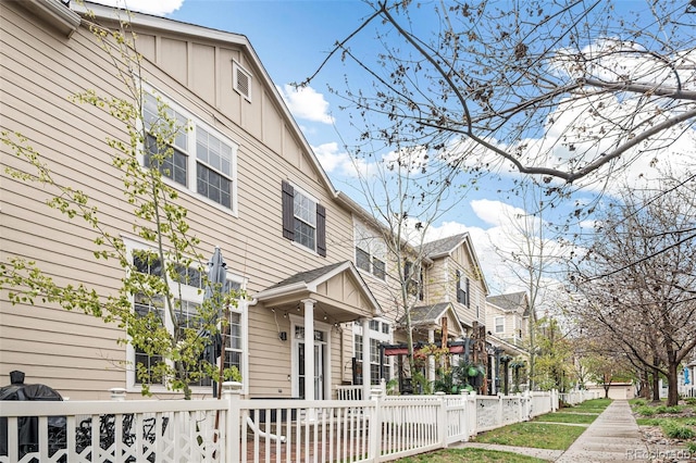 view of side of home featuring a residential view, board and batten siding, and fence