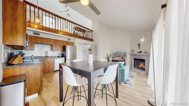 kitchen featuring a ceiling fan, tasteful backsplash, dark countertops, stainless steel appliances, and light wood-style floors