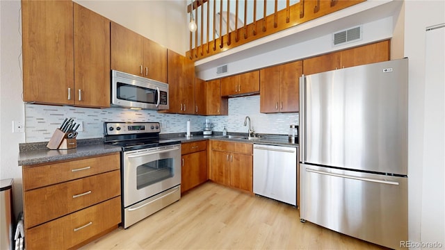 kitchen with visible vents, a sink, appliances with stainless steel finishes, dark countertops, and brown cabinets