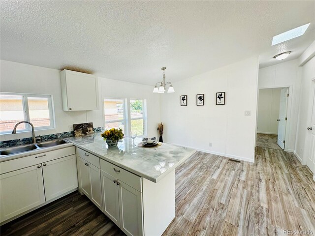 kitchen with light hardwood / wood-style floors, kitchen peninsula, a healthy amount of sunlight, and sink