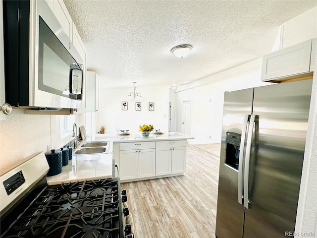 kitchen with sink, a textured ceiling, light hardwood / wood-style flooring, white cabinetry, and stainless steel appliances