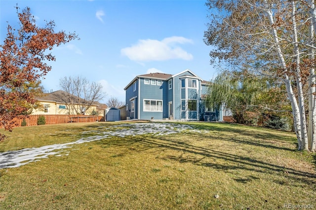 rear view of house with a storage unit and a lawn