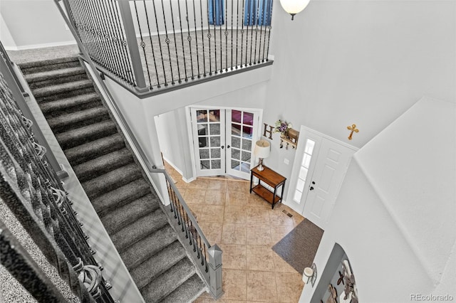 stairs featuring a high ceiling, tile patterned floors, and french doors