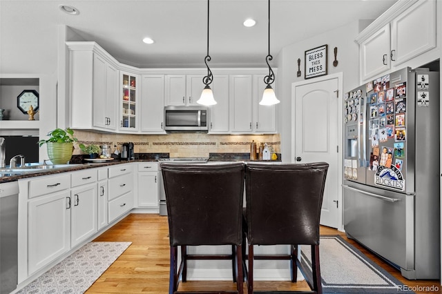 kitchen featuring a breakfast bar, appliances with stainless steel finishes, white cabinets, and hanging light fixtures