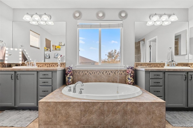 bathroom featuring tile patterned flooring, vanity, and tiled bath