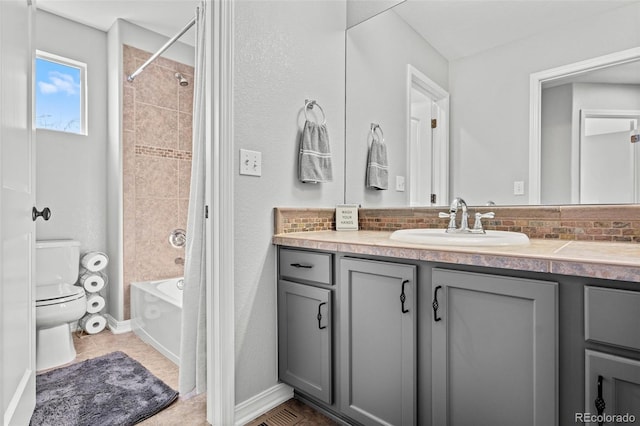 full bathroom featuring vanity, decorative backsplash, tiled shower / bath combo, and toilet