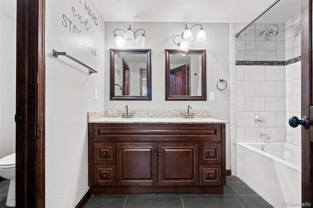 full bathroom featuring tile patterned floors, vanity, tiled shower / bath, and toilet