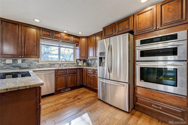 kitchen with sink, backsplash, stainless steel appliances, and light wood-type flooring