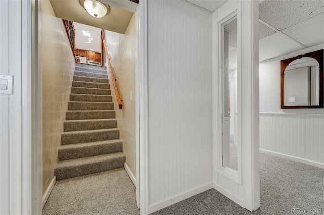 stairs with carpet flooring and a drop ceiling