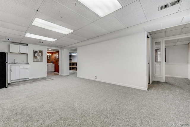 unfurnished living room with light colored carpet and a drop ceiling