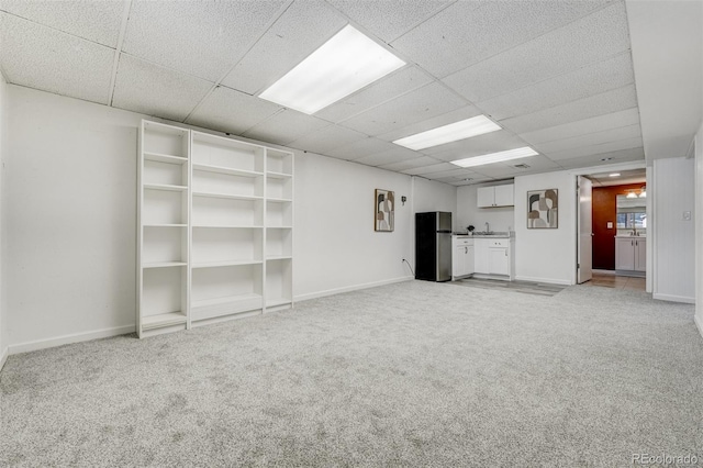 unfurnished living room with a paneled ceiling, sink, and light carpet