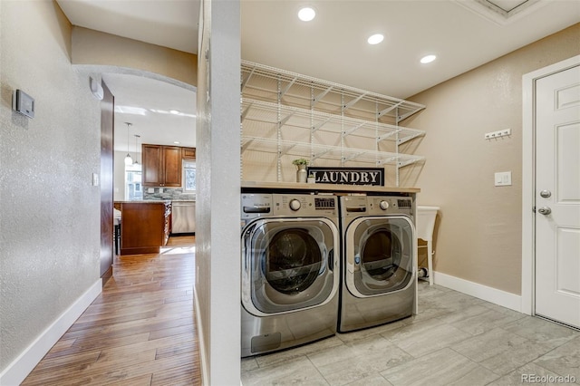 washroom with washing machine and dryer and light wood-type flooring