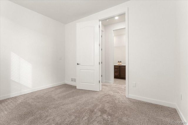 empty room with baseboards, visible vents, and light colored carpet